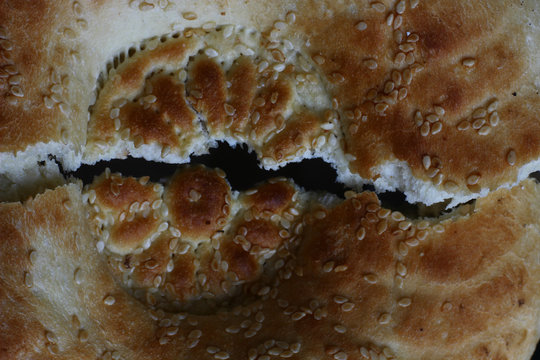 roken bread cake with sesame seeds on a dark background