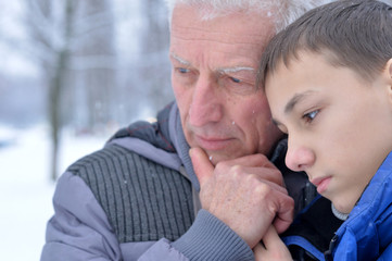 Close up portrait of senior man and boy standing outdoors in winter