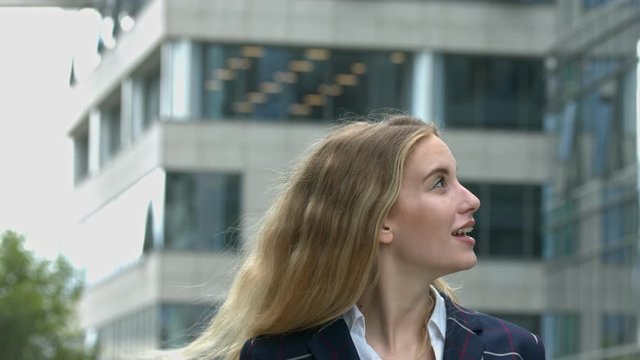 Beautiful business woman looks around office buildings with fascination. First day at work or recruit for work in a corporation. Slow motion, 4k, UHD