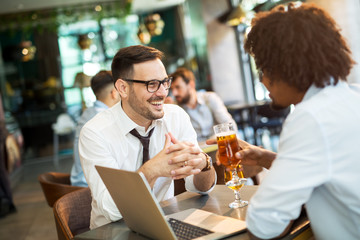 Two businessmen working on the go on a laptop together in a cafe.