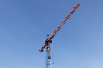 tower of a construction red crane against a blue sky