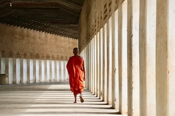 Rear view of a buddhist monk walking along the corridor of the Shwezigon temple in Bagan, Myanmar - Powered by Adobe