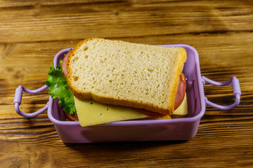 Lunch box with sandwiches on a wooden table