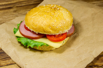 Fresh delicious homemade cheeseburger on brown paper on wooden table