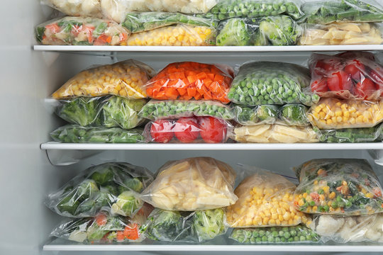 Plastic bags with different frozen vegetables in refrigerator
