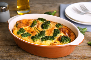 Tasty broccoli casserole in baking dish on wooden table