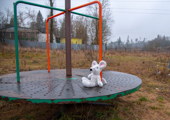 A toy mouse, forgotten on the merry-go-round, in rainy cloudy weather.
