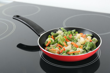 Cooking tasty frozen vegetable mix on induction stove
