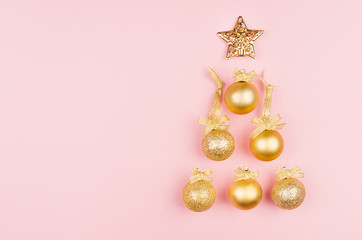 Elegant christmas tree of golden balls, star on pastel pink background as decorative border, top view.