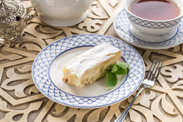 Homemade apple sponge cake with cup of black tea on oriental wooden table