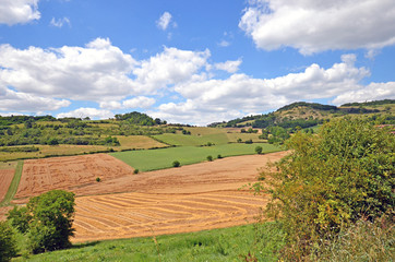 Beautiful rural landscape with blue sky, spectacular clouds and wheat fields in Auvergne region in France