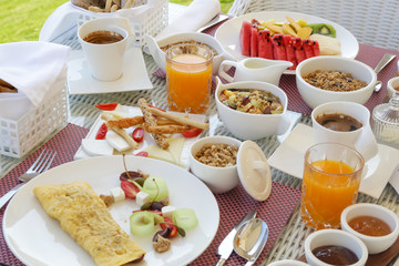 Beautifully arranged breakfast table with coffee, orange juice, pastry, fruits, cereals and eggs