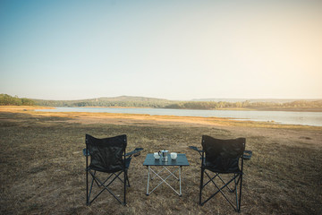 Outdoor two empty chairs with picnic table and moka pot coffee for Camping.