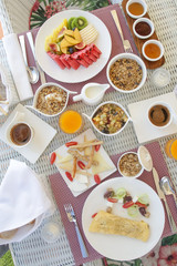Beautifully arranged breakfast table with coffee, orange juice, pastry, fruits, cereals and eggs, top view