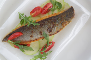 Fish fillet served with fresh cherry tomato and arugula