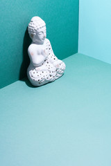 White ceramic buddha figurine on a blue background