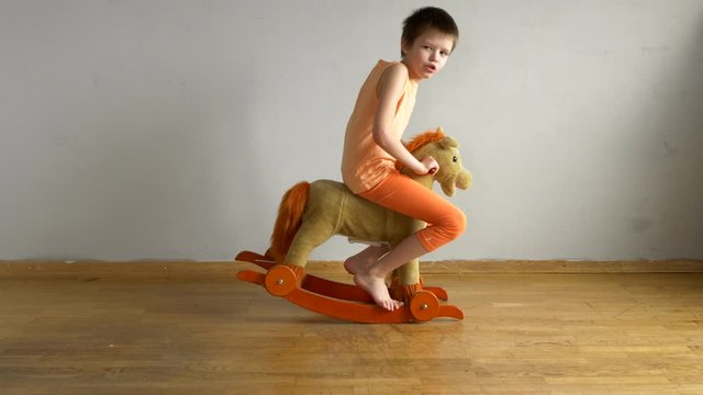big boy, a schoolboy, riding a little swinging toy horse for kids. child enjoys recalling his childhood