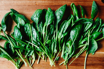 Top view of fresh spinach leaves on a wooden cutting board. Healthy vegetarian eating concept.