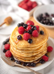 Sweet homemade pancakes with raspberries on white plate with honey deeper.