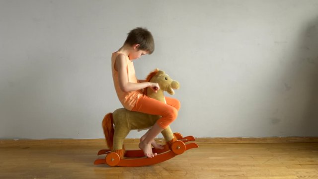 big boy, a schoolboy, riding a little swinging toy horse for kids. child enjoys recalling his childhood