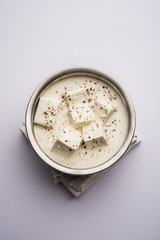 Paneer Dum Kali Mirch / Kalimirch, prepared in a white creamy gravy and black pepper powder sprinkled over it. served in a bowl. Selective focus