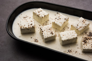 Paneer Dum Kali Mirch / Kalimirch, prepared in a white creamy gravy and black pepper powder sprinkled over it. served in a bowl. Selective focus