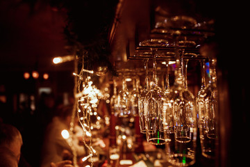 Glasses of wine. Glasses hanging above the bar in the restaurant. Empty glasses for wine. Wine and martini glasses in shelf above a bar rack in restaurant. blue lights, blue background, night life