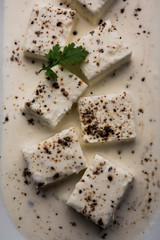 Paneer Dum Kali Mirch / Kalimirch, prepared in a white creamy gravy and black pepper powder sprinkled over it. served in a bowl. Selective focus