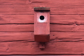 Wooden birdhouse on a wooden house facade