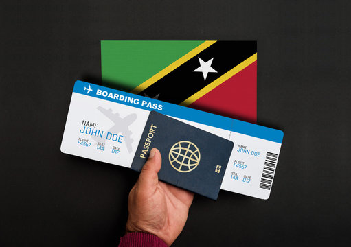 Hand holds passport and boarding pass with flag of Saint Kitts and Nevis
