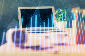 Stock market chart hologram drawn on personal computer background. Double exposure. Concept of...