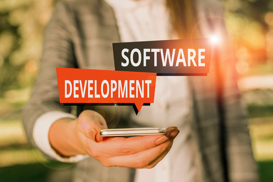 Text sign showing Software Development. Business photo showcasing software is created using a specific programming Woman in grey suites holds mobile phone