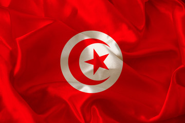 photograph of the beautiful colored national flag of the modern African state of Tunisia on textured fabric, concept of tourism, emigration, economics and politics, close-up