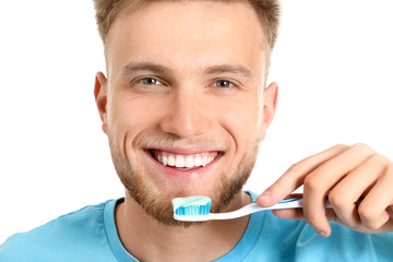 Young man brushing teeth on white background