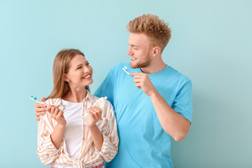 Young couple brushing teeth on color background