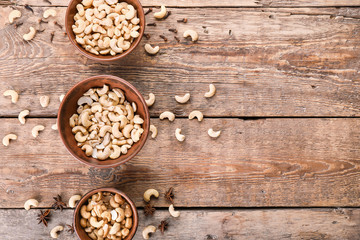 Obraz na płótnie Canvas Bowls with tasty cashew nuts on wooden background