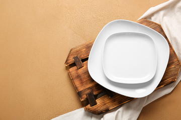 Empty plates, board and napkin on color background