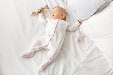 Cute baby with toy sleeping in bed