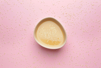 Bowl of tasty tahini on color background