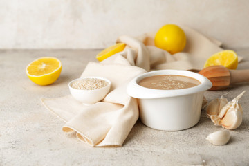 Bowl of tasty tahini on grey background