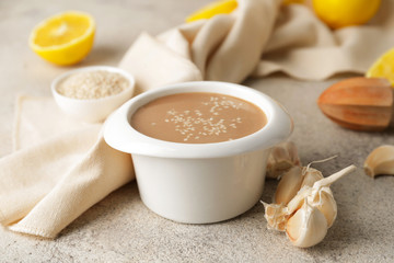 Bowl of tasty tahini on grey background