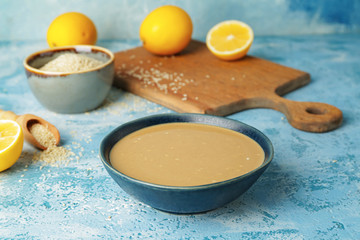 Bowl of tasty tahini on color background