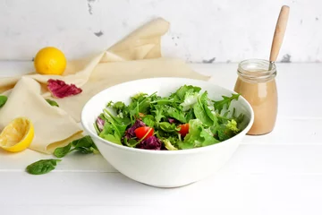 Poster Bowl with vegetable salad and jar of tasty tahini on table © Pixel-Shot
