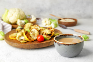 Bowl of tasty tahini and grilled vegetables on table