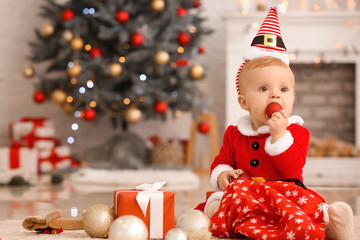 Obraz na płótnie Canvas Cute little baby in Santa Claus costume and with Christmas gift at home