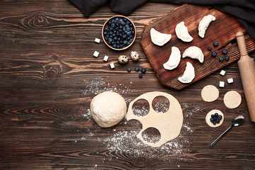 Raw dough and dumplings with ingredients on wooden background