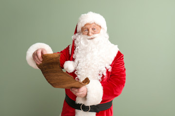 Fototapeta na wymiar Santa Claus reading wish list on color background