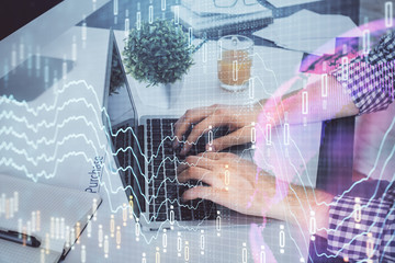 Double exposure of graph with man typing on computer in office on background. Concept of hard work.