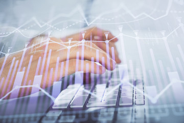 Multi exposure of graph with man typing on computer in office on background. Concept of hard work. Closeup.