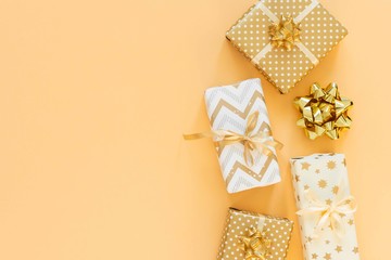 Holiday background in gold colors, gift boxes with bows on a gold background, flat lay, top view, copy space